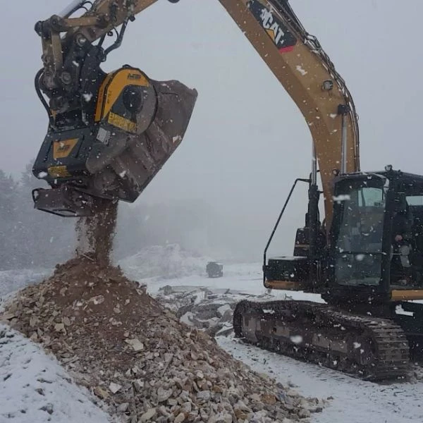 Cuchara trituradora MB BF70.2 S4 operando con nieve y escombros.