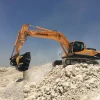 Cuchara trituradora MB BF90.3 S4 operando en cantera blanca con excavadora Hyundai.