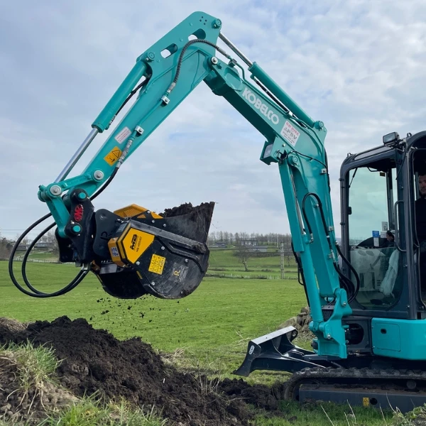 Cuchara MB-HDS307 realizando aireación de terreno húmedo con excavadora ligera en campo abierto.