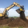 Cuchara cribadora MB-HDS320 de MB Crusher acoplada a Komatsu seleccionando tierra vegetal.