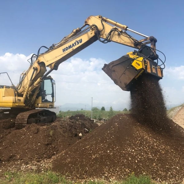 Cuchara cribadora MB-HDS320 de MB Crusher acoplada a Komatsu seleccionando tierra vegetal.