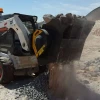 MB-L120 S2 Cuchara Trituradora MB triturando piedra seca con polvo visible en obra.