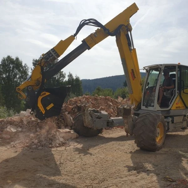 Cuchara trituradora MB-L140 S2 de MB acoplada a máquina Caterpillar con cinta transportadora.