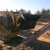 Cuchara trituradora MB-L140 S2 de MB acoplada a minicargadora trabajando en obra.