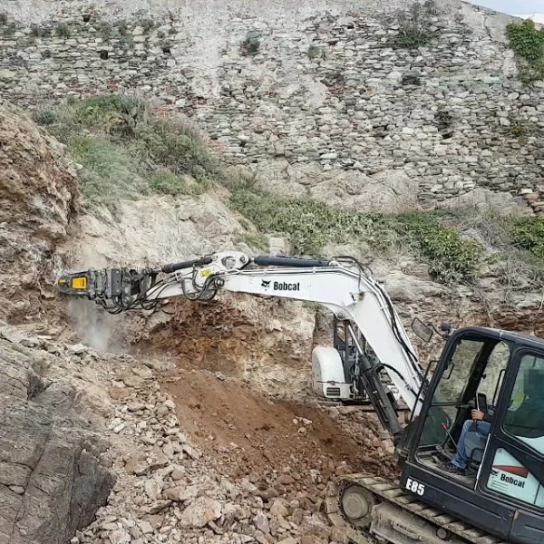 MB-R500 de MB Crusher fresando roca con excavadora Bobcat en entorno escarpado