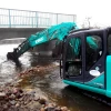 Excavadora utilizando MB-R700 de MB Crusher para fresado de asfalto y demolición vial.