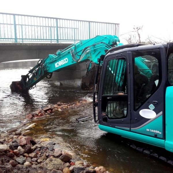 Excavadora utilizando MB-R700 de MB Crusher para fresado de asfalto y demolición vial.