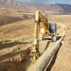 Excavadora JCB con fresadora MB-R800 demoliendo muro vertical de hormigón armado en obra urbana.