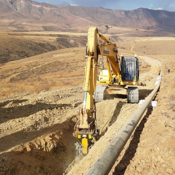 Excavadora JCB con fresadora MB-R800 demoliendo muro vertical de hormigón armado en obra urbana.