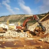 Cuchara MB-S23 montada en excavadora operando en cantera.