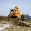 Venieri 10.23E con vista trasera, excavando en un terreno de obra con su brazo extendido.