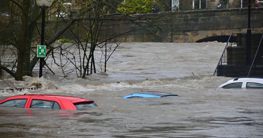 Inundación urbana con vehículos sumergidos donde la maquinaria para Protección Civil es crucial para el rescate y evacuación.