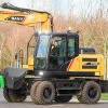 Excavadora de ruedas SANY SY155W en movimiento, mostrando su versatilidad y eficiencia en entornos urbanos y rurales.