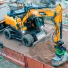 Excavadora de ruedas SANY SY155W trabajando en una obra urbana, destacando su versatilidad y precisión en espacios reducidos.