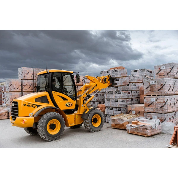 Pala cargadora Venieri 2.63 H amarilla manipulando pallets de materiales de construcción en obra bajo cielo nublado.