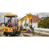 SANY SY16C maniobrando con cazo en calle; miniexcavadora giratoria compacta de cabina abierta con tren de rodaje extensible.