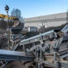 Criba eléctrica móvil CAMS UVS 25/2 trabajando en obra de reciclaje con excavadora cargando material.